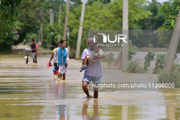 People are walking through a flooded road following rains in the aftermath of Cyclone Remal, in Nagaon district of Assam, India, on June 2,...