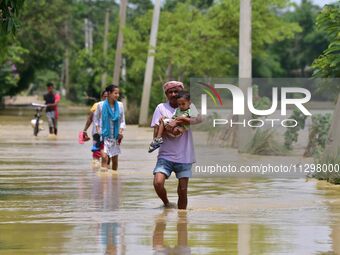 People are walking through a flooded road following rains in the aftermath of Cyclone Remal, in Nagaon district of Assam, India, on June 2,...