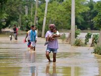 People are walking through a flooded road following rains in the aftermath of Cyclone Remal, in Nagaon district of Assam, India, on June 2,...