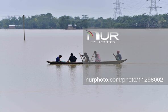 People are traveling on a boat to cross flood water in the aftermath of Cyclone Remal, in Nagaon district of Assam, India, on June 2, 2024. 