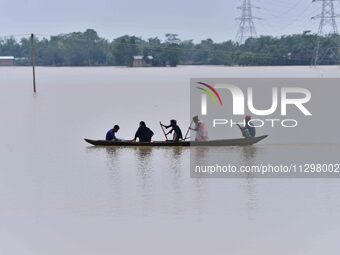 People are traveling on a boat to cross flood water in the aftermath of Cyclone Remal, in Nagaon district of Assam, India, on June 2, 2024....