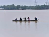 People are traveling on a boat to cross flood water in the aftermath of Cyclone Remal, in Nagaon district of Assam, India, on June 2, 2024....