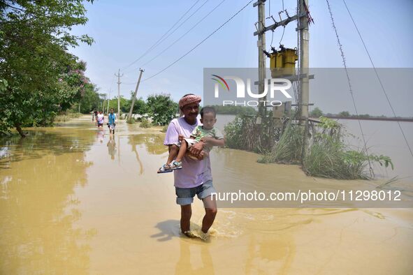 People are walking through a flooded road following rains in the aftermath of Cyclone Remal, in Nagaon district of Assam, India, on June 2,...