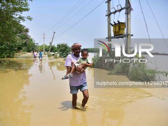 People are walking through a flooded road following rains in the aftermath of Cyclone Remal, in Nagaon district of Assam, India, on June 2,...