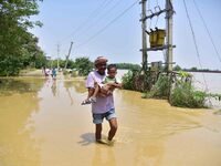 People are walking through a flooded road following rains in the aftermath of Cyclone Remal, in Nagaon district of Assam, India, on June 2,...