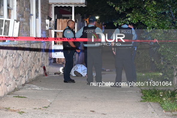 Chicago Police are canvassing the area for evidence as a male victim who was shot twenty-five times and killed is covered with a sheet. A ma...