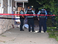 Chicago Police are canvassing the area for evidence as a male victim who was shot twenty-five times and killed is covered with a sheet. A ma...