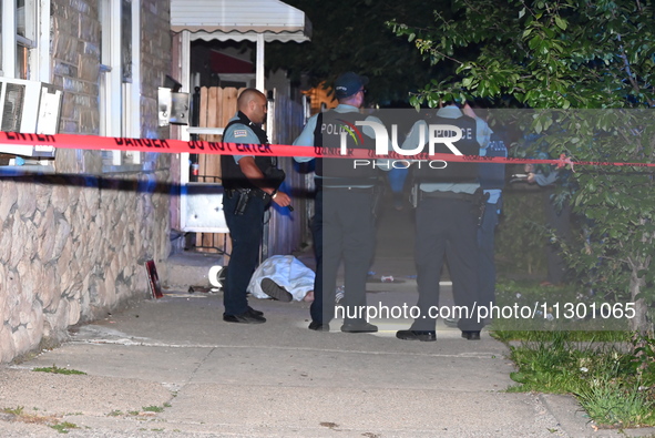 Chicago Police are canvassing the area for evidence as a male victim who was shot twenty-five times and killed is covered with a sheet. A ma...