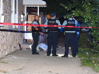 Chicago Police are canvassing the area for evidence as a male victim who was shot twenty-five times and killed is covered with a sheet. A ma...