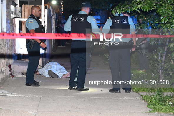 Chicago Police are canvassing the area for evidence as a male victim who was shot twenty-five times and killed is covered with a sheet. A ma...