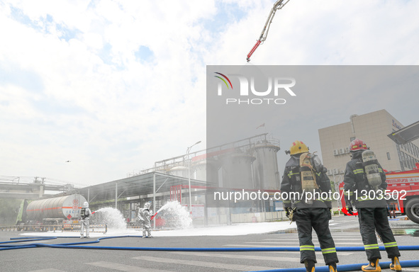 Personnel are cooling down a burning storage tank during an emergency drill for handling a dangerous chemical leak fire in Deqing county, Hu...