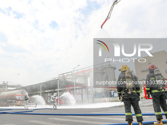 Personnel are cooling down a burning storage tank during an emergency drill for handling a dangerous chemical leak fire in Deqing county, Hu...