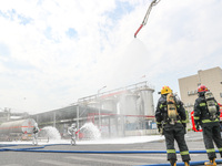 Personnel are cooling down a burning storage tank during an emergency drill for handling a dangerous chemical leak fire in Deqing county, Hu...