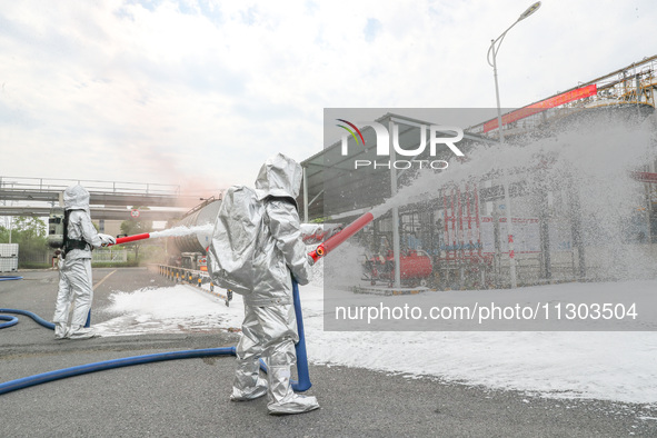 Personnel are cooling down a burning storage tank during an emergency drill for handling a dangerous chemical leak fire in Deqing county, Hu...