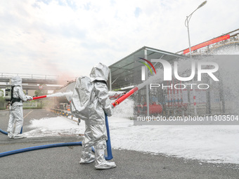 Personnel are cooling down a burning storage tank during an emergency drill for handling a dangerous chemical leak fire in Deqing county, Hu...