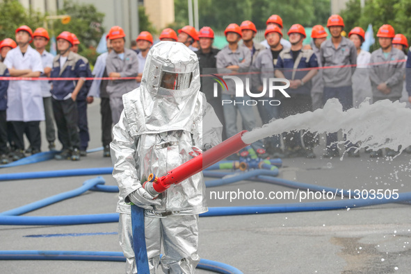 Personnel are cooling down a burning storage tank during an emergency drill for handling a dangerous chemical leak fire in Deqing county, Hu...