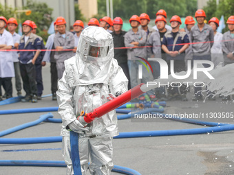 Personnel are cooling down a burning storage tank during an emergency drill for handling a dangerous chemical leak fire in Deqing county, Hu...