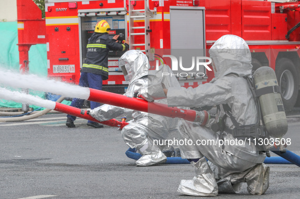 Personnel are cooling down a burning storage tank during an emergency drill for handling a dangerous chemical leak fire in Deqing county, Hu...