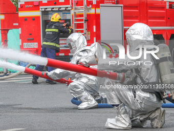 Personnel are cooling down a burning storage tank during an emergency drill for handling a dangerous chemical leak fire in Deqing county, Hu...