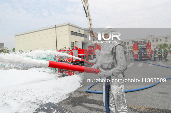 Personnel are cooling down a burning storage tank during an emergency drill for handling a dangerous chemical leak fire in Deqing county, Hu...