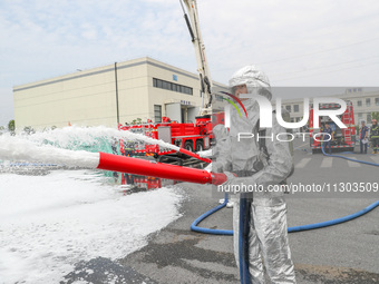 Personnel are cooling down a burning storage tank during an emergency drill for handling a dangerous chemical leak fire in Deqing county, Hu...