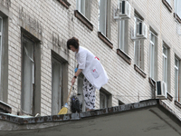 A healthcare worker is sweeping away glass shards from the roof of a portico at a hospital damaged by the falling debris of downed Russian m...