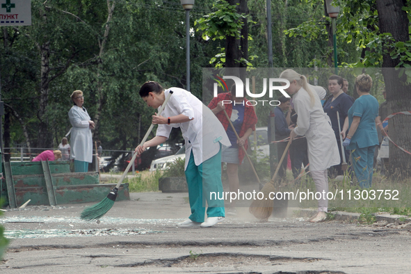 Healthcare workers are sweeping away glass shards outside a hospital damaged by the falling debris of downed Russian missiles in Dnipro, Ukr...