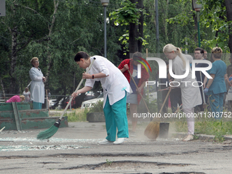 Healthcare workers are sweeping away glass shards outside a hospital damaged by the falling debris of downed Russian missiles in Dnipro, Ukr...