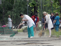 Healthcare workers are sweeping away glass shards outside a hospital damaged by the falling debris of downed Russian missiles in Dnipro, Ukr...