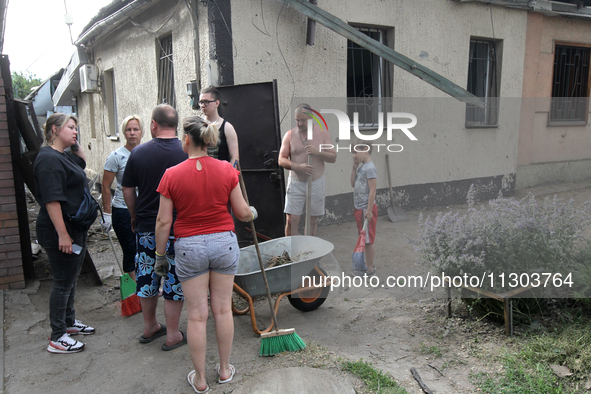 Locals are gathering outside a house damaged by the falling debris of downed Russian missiles in Dnipro, Ukraine, on June 4, 2024. As report...