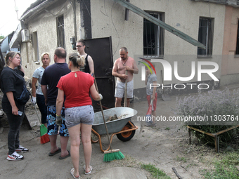 Locals are gathering outside a house damaged by the falling debris of downed Russian missiles in Dnipro, Ukraine, on June 4, 2024. As report...