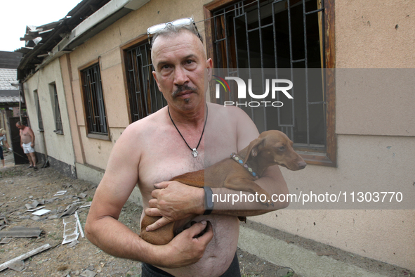 A man is holding a dog as he is speaking to the press following a nighttime Russian missile attack in Dnipro, Ukraine, on June 4, 2024. As r...