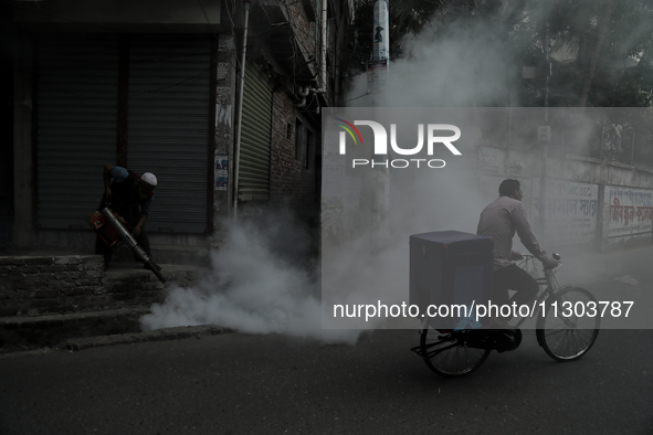 A municipal worker from the Department of Health Service is fumigating vapor to stem the spread of dengue while a cyclist is passing by in D...