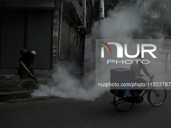 A municipal worker from the Department of Health Service is fumigating vapor to stem the spread of dengue while a cyclist is passing by in D...