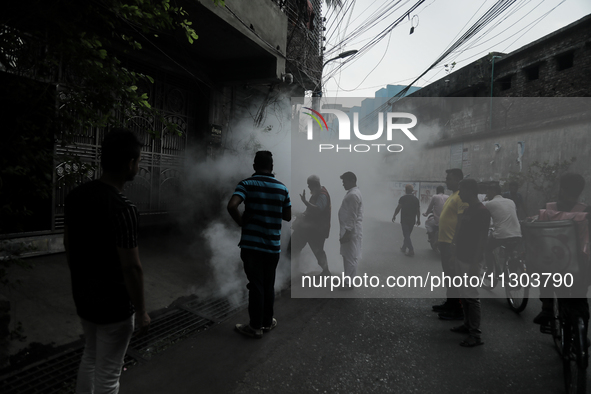 A municipal worker from the Department of Health Service is fumigating vapor to stem the spread of dengue while people are gathering to watc...