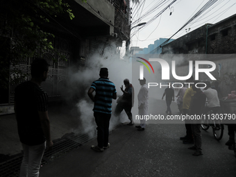 A municipal worker from the Department of Health Service is fumigating vapor to stem the spread of dengue while people are gathering to watc...