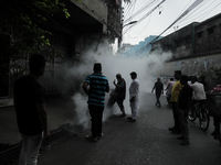 A municipal worker from the Department of Health Service is fumigating vapor to stem the spread of dengue while people are gathering to watc...