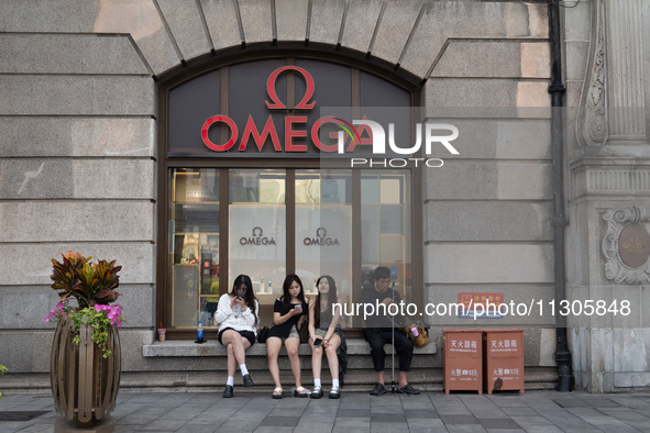 Tourists are sitting in front of an OMEGA watch store in Shanghai, China, on June 4, 2024. 