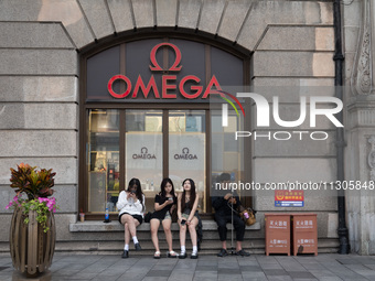 Tourists are sitting in front of an OMEGA watch store in Shanghai, China, on June 4, 2024. (