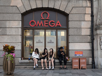 Tourists are sitting in front of an OMEGA watch store in Shanghai, China, on June 4, 2024. (