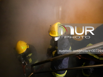 Nepali firefighters from the Armed Police Force, Nepal Army, and the Fire Brigade are dousing a fire that broke out in a warehouse in Kathma...