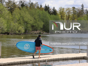 A man is carrying a paddleboard along Lake Wilcox in Richmond Hill, Ontario, Canada, on May 12, 2024. (