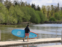 A man is carrying a paddleboard along Lake Wilcox in Richmond Hill, Ontario, Canada, on May 12, 2024. (