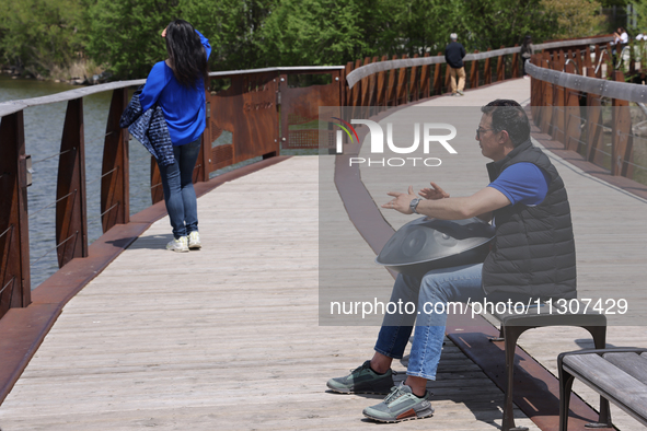 A man is playing a rhythmic tune on a musical instrument along a boardwalk by Lake Wilcox in Richmond Hill, Ontario, Canada, on May 12, 2024...