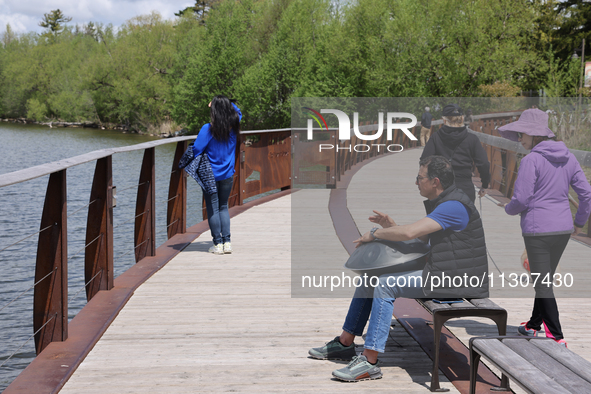 A man is playing a rhythmic tune on a musical instrument along a boardwalk by Lake Wilcox in Richmond Hill, Ontario, Canada, on May 12, 2024...