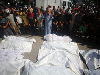 Palestinians are praying over the bodies of people killed in Israeli bombardment of a house in al-Maghazi refugee camp, at the Al-Aqsa Marty...