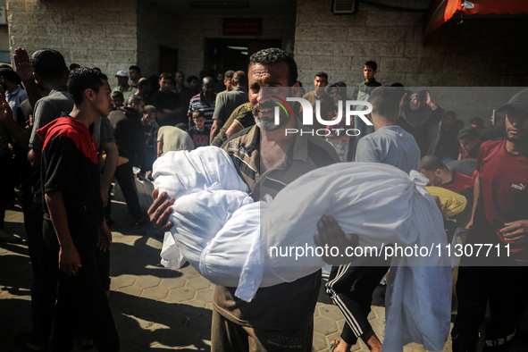 A Palestinian man is carrying the body of a young relative, killed in Israeli bombardment of a house in al-Maghazi refugee camp, at the Al-A...