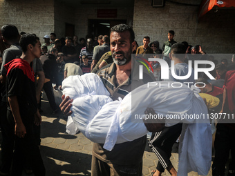 A Palestinian man is carrying the body of a young relative, killed in Israeli bombardment of a house in al-Maghazi refugee camp, at the Al-A...