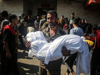 A Palestinian man is carrying the body of a young relative, killed in Israeli bombardment of a house in al-Maghazi refugee camp, at the Al-A...