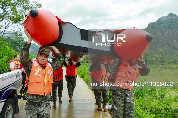 Armed police officers are carrying rubber boats to the disaster area in Shilong village, Gongchuan Township, Dahua county, Hechi city, South...